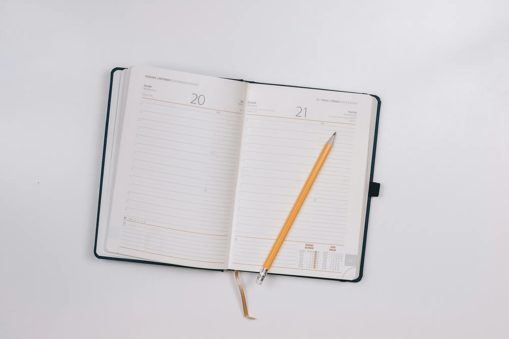 Agenda abierta por dos días con un lápiz encima, sobre fondo blanco